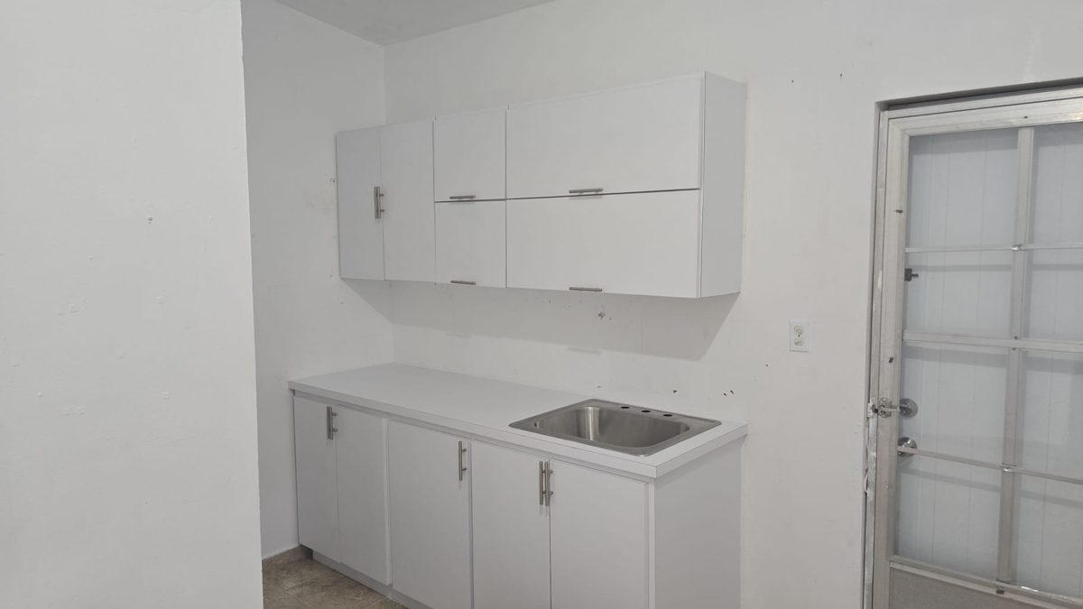 White kitchenette with wall and base cabinets and a stainless sink