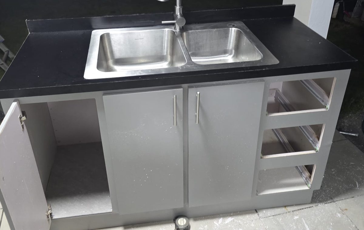 Outdoor kitchen base cabinet with black countertop and double stainless sink